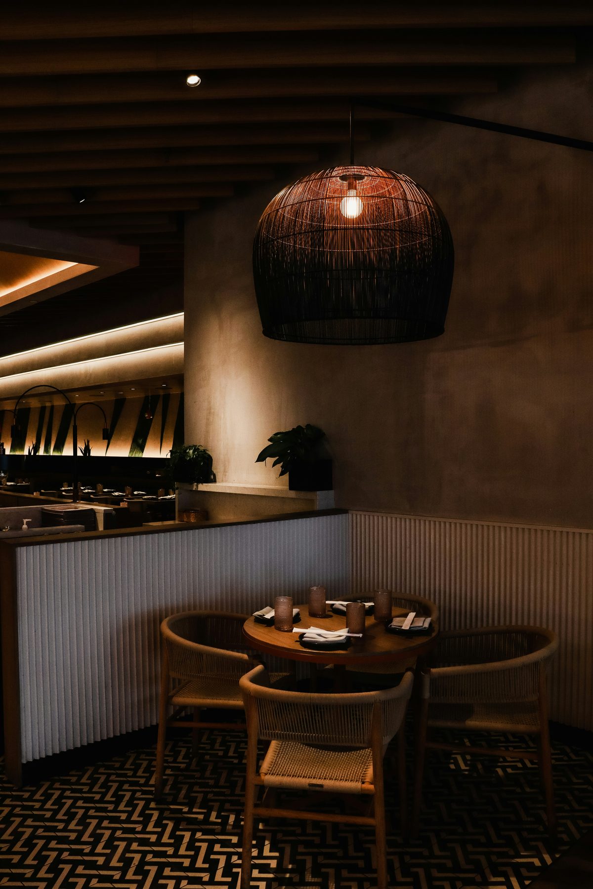 A quiet corner of the dining room: a round table for four beneath a woven pendant lamp